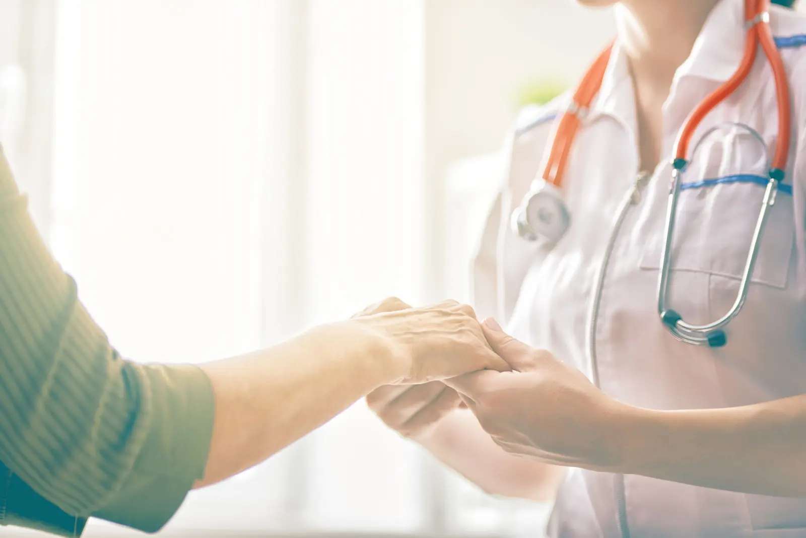 A clinician holding a patient's hands in reassurance