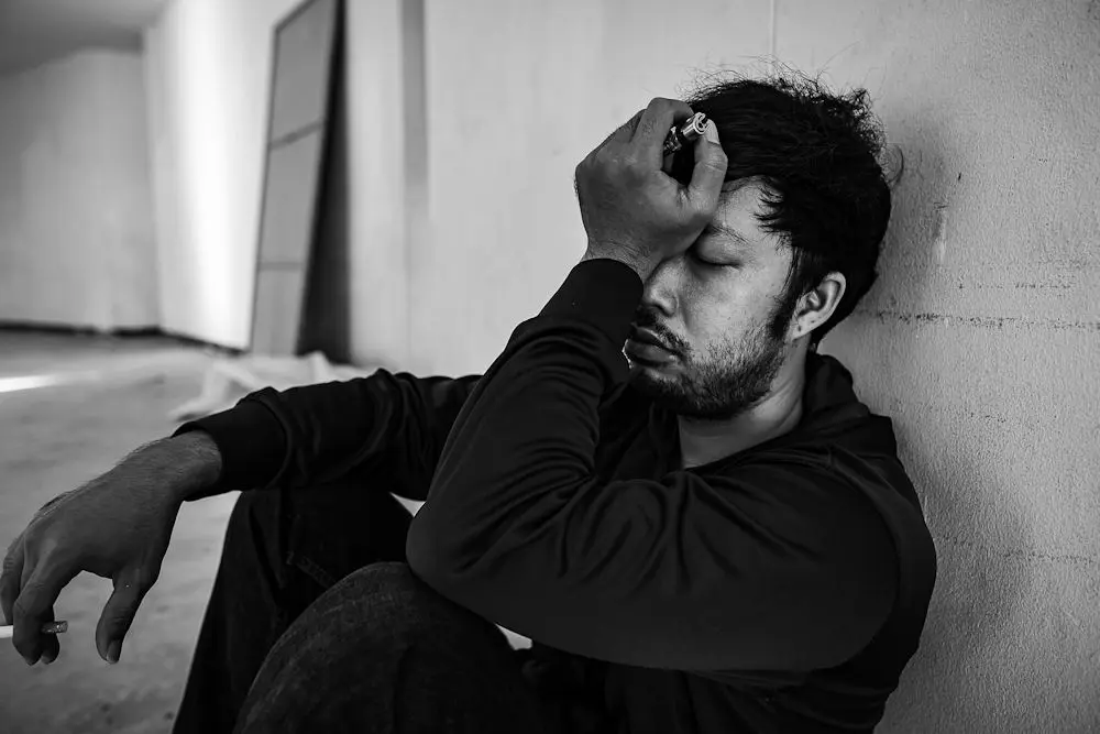 A man struggling with substance abuse sitting against a wall