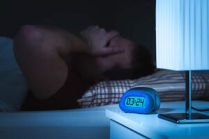 man sleeping next to alarm clock