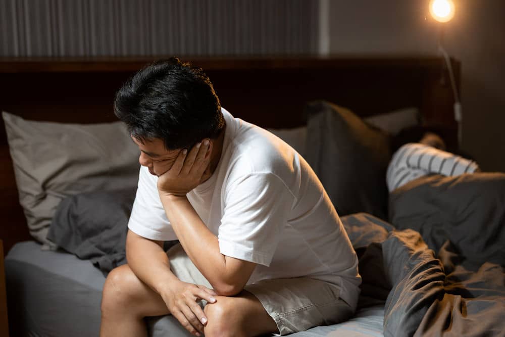 man with alcohol addiction sitting on his bed