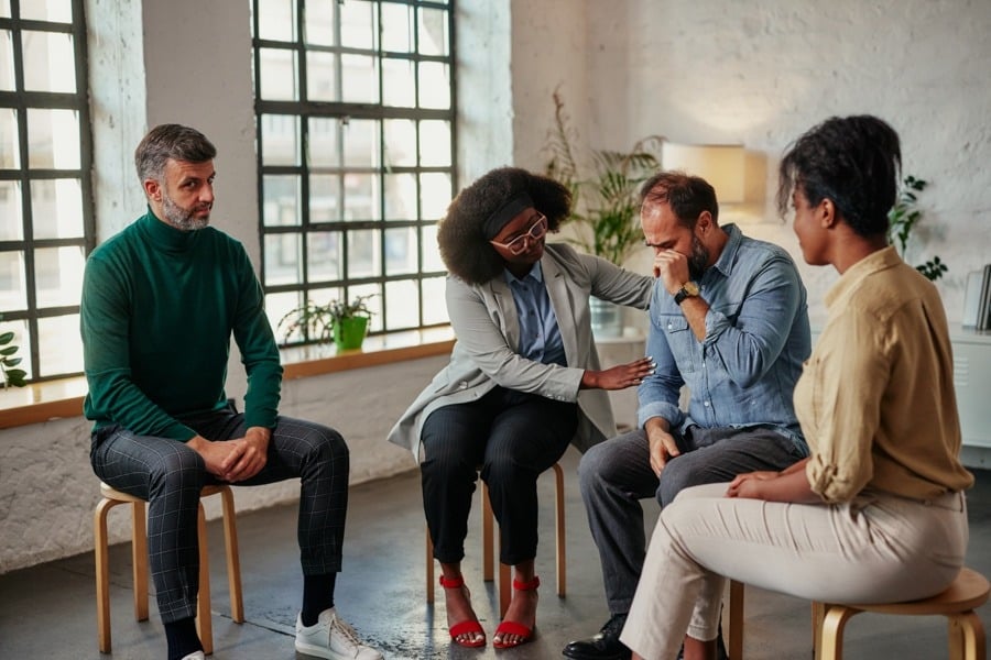 a man being comforted during group therapy